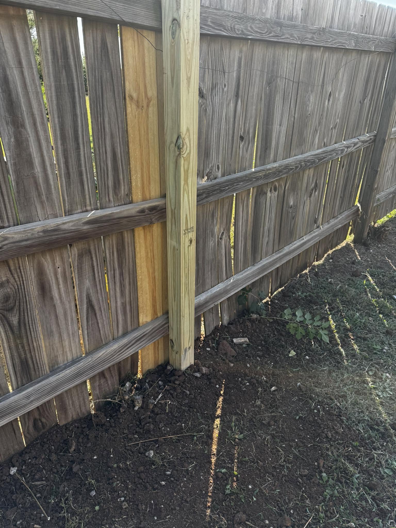 New fence post and pickets set along a wooden privacy fence