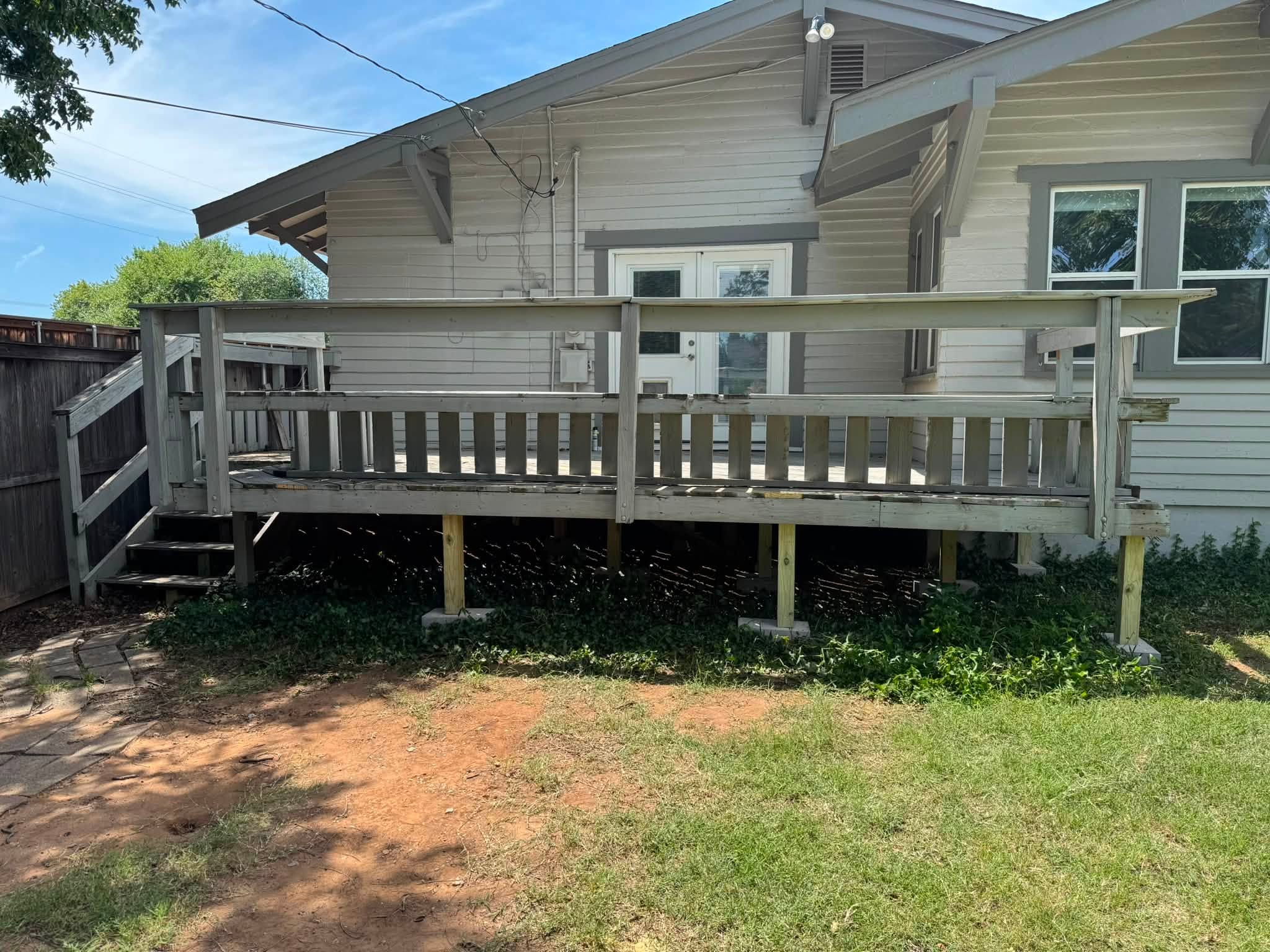 Raised wooden deck with railing, stairs, and support posts