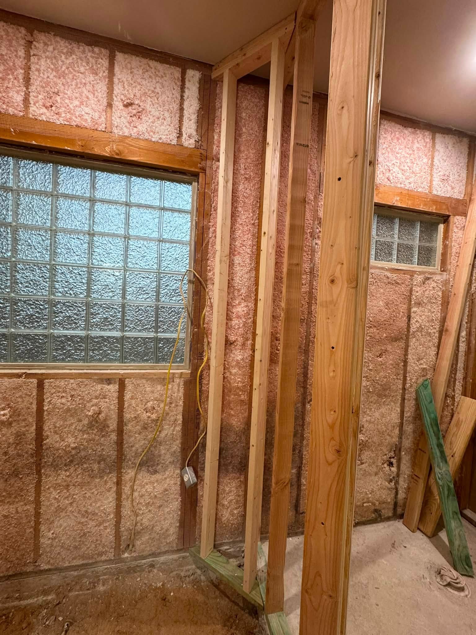 New wood stud framing at a corner beside glass-block windows