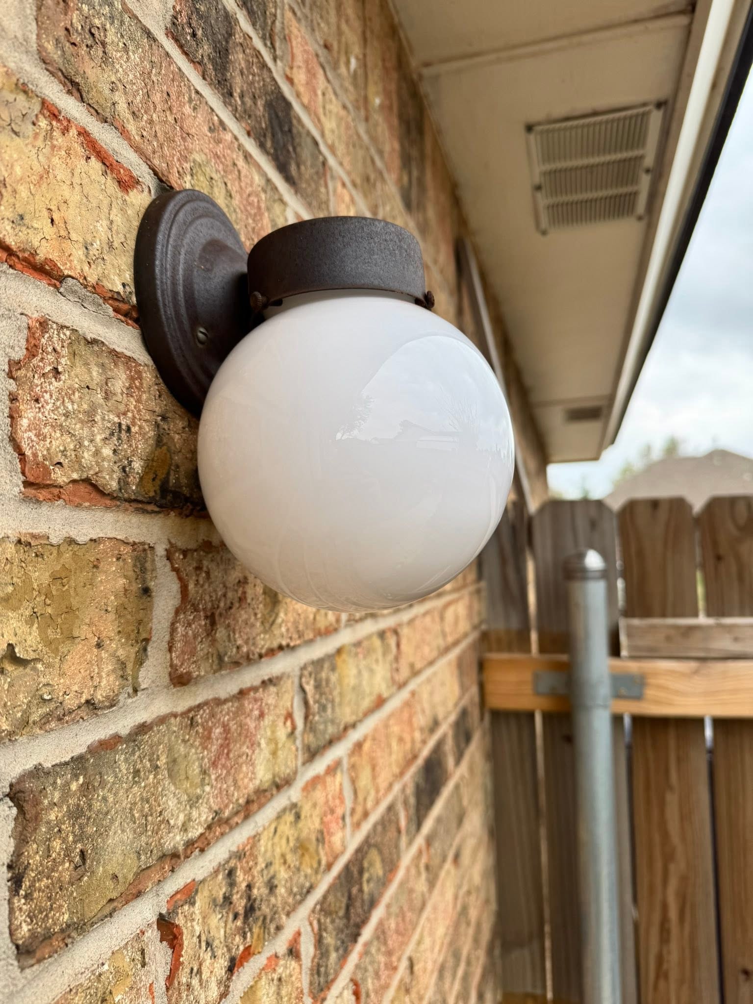 Globe wall light fixture installed on a brick exterior