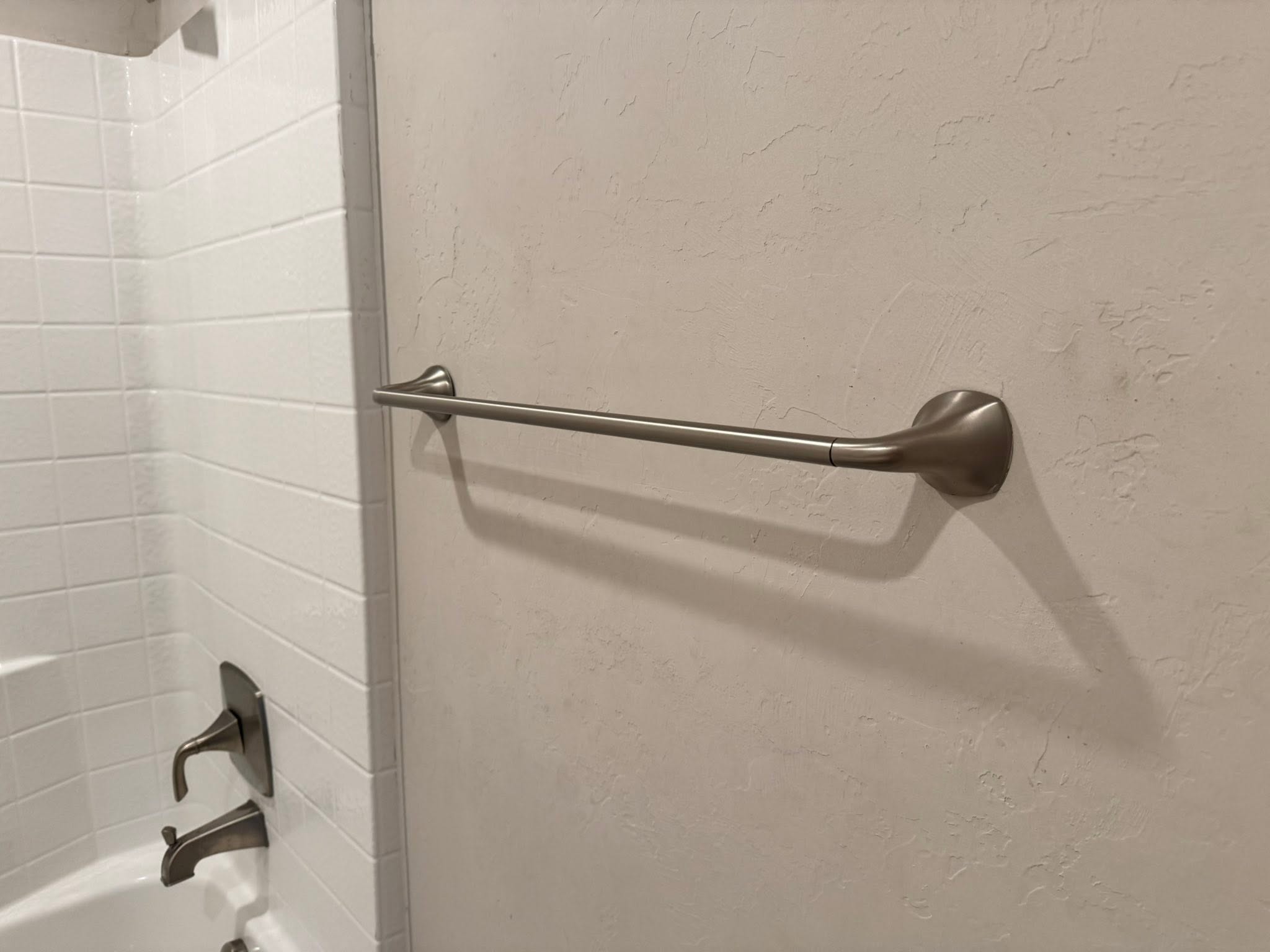 Bathroom safety bar installed next to a tiled shower